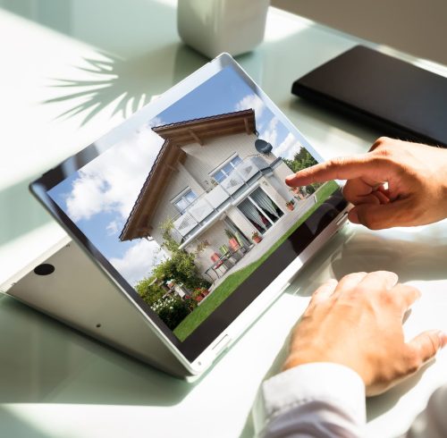 Businessman checking house on laptop Close-up of businessman's hand checking house on laptop